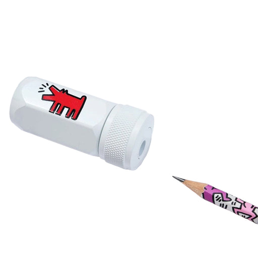 White pencil sharpener with red dog design and a pink and black patterned pencil on a white background