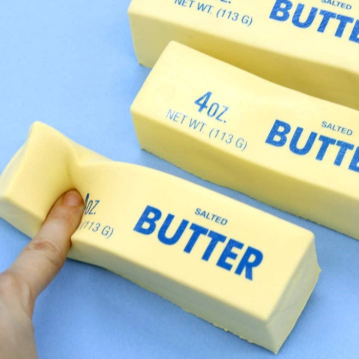 Three blocks of salted butter squishy stress toys on a blue background