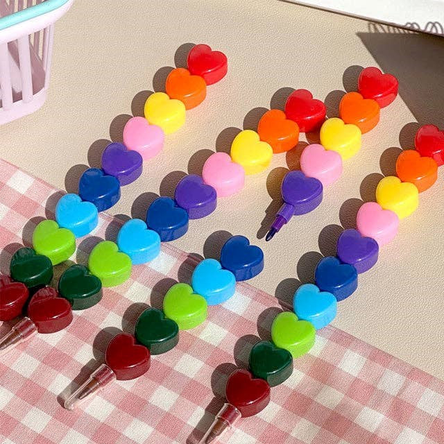 Colourful heart-shaped stackable crayons arranged on a checkered fabric surface.