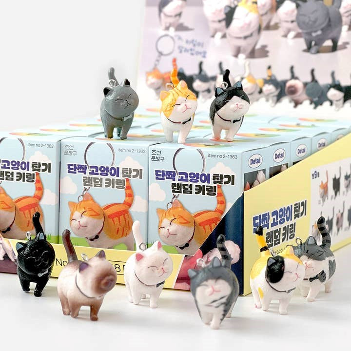 Cat-themed figurines in front of boxes with cartoon cat illustrations on a white background