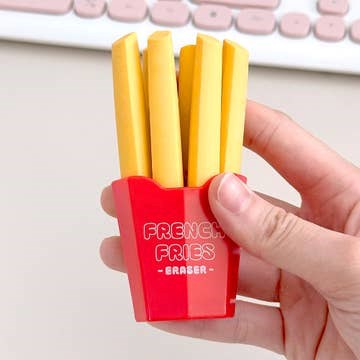 Hand holding a small red container with yellow 'fries' erasers on a light background