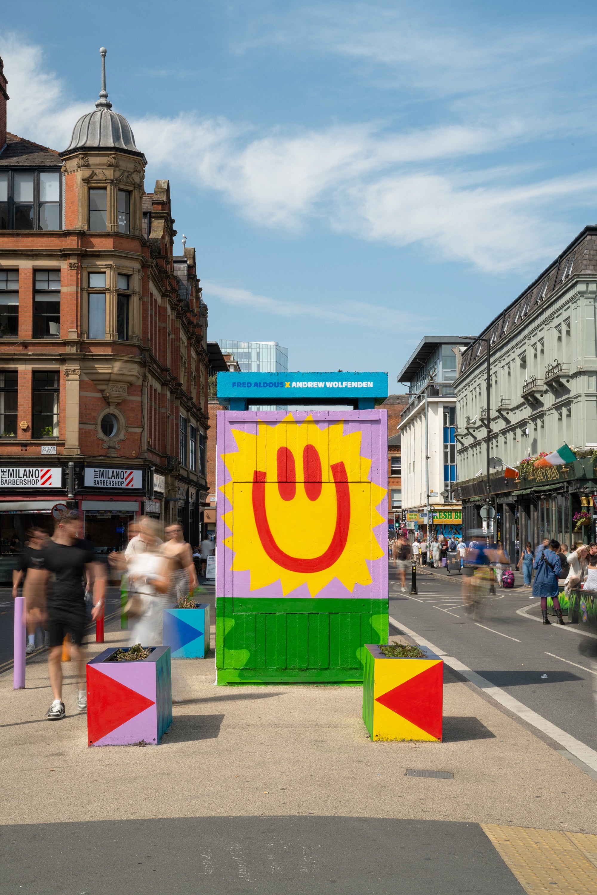 Colorful geometric art installation on a city street with people walking by
